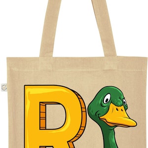 May include: A beige canvas tote bag with a yellow letter R and a green duck head illustration. The duck has a yellow beak and white feathers around its neck.