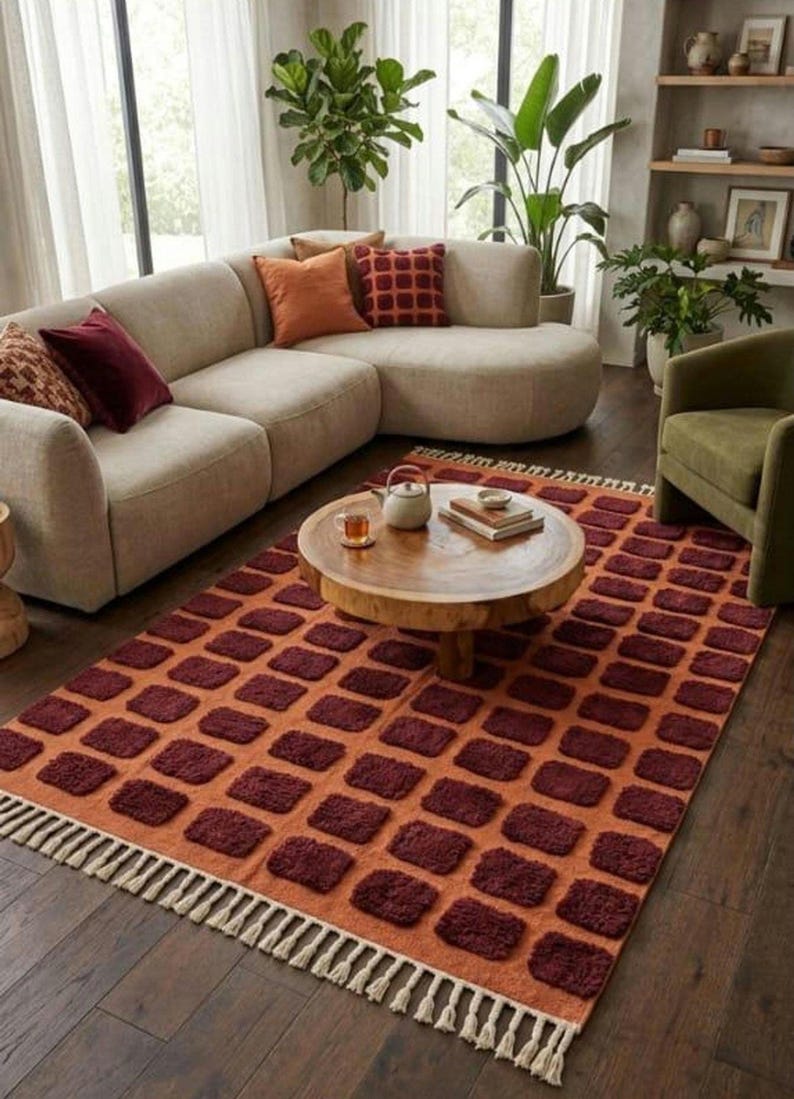Dark red-orange checkered handwoven wool rug with white tassel fringe; boho modern tassel-edge rug for a reading nook.