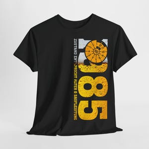 Könnte beinhalten: Schwarzes T-Shirt mit gelb-weißem Grafikdesign. Das Design zeigt die Zahl "85", eine Bieruhr und den Text "ZUSTAND ENTSPRICHT ALTER & SAUFLEISTUNG".