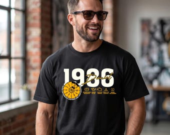 May include: A black short-sleeved t-shirt featuring the large white text 1986, the name Daniel in yellow script, a yellow circular gauge graphic with the number 40, and various small yellow car dashboard warning light icons with German text.