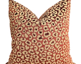 May include: A red and gold velvet cushion with a leopard print pattern.