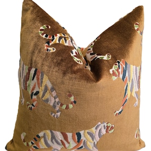 Peut inclure: Un oreiller en velours marron avec un motif de tigre brod&eacute; color&eacute;. L'oreiller pr&eacute;sente plusieurs tigres dans diff&eacute;rentes poses, avec des rayures dans des tons de rose, vert, orange et noir.