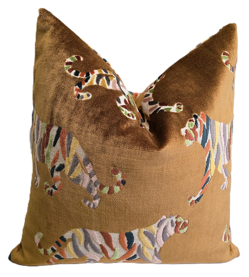 Peut inclure: Un oreiller en velours marron avec un motif de tigre brod&eacute; color&eacute;. L'oreiller pr&eacute;sente plusieurs tigres dans diff&eacute;rentes poses, avec des rayures dans des tons de rose, vert, orange et noir.