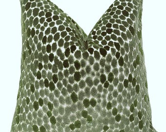 May include: A decorative pillow with a green spotted pattern. The pillow has a soft, textured appearance, with varying shades of green dots against a lighter background. The pillow is square-shaped and appears to be made of a plush fabric.