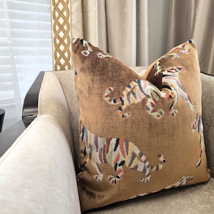 Peut inclure: Un coussin en velours marron avec un motif de tigre color&eacute;. Le coussin est pos&eacute; sur un canap&eacute; beige.