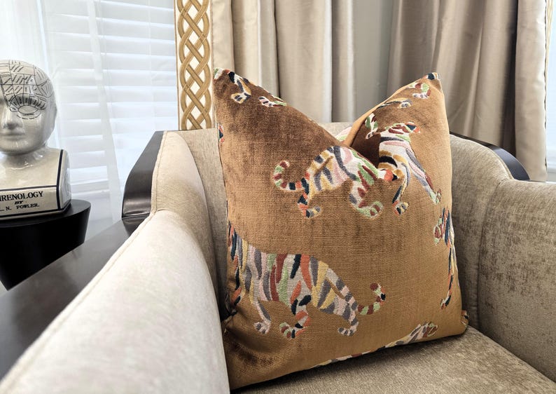 Peut inclure: Un coussin en velours marron avec un motif de tigre color&eacute;. Le coussin est pos&eacute; sur un canap&eacute; beige.