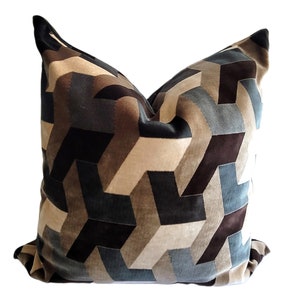 May include: A decorative pillow with a geometric pattern in shades of brown, beige, and blue. The pillow is made of a soft, plush fabric.