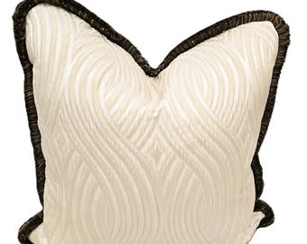 May include: A white pillow with a textured, wavy pattern and a black and brown trim.