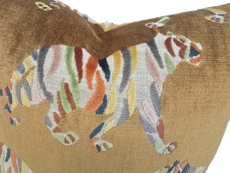 Peut inclure: Un coussin en velours marron avec un motif de tigre brod&eacute; color&eacute;. Le tigre est ray&eacute; de nuances de rose, jaune, vert, orange et bleu.