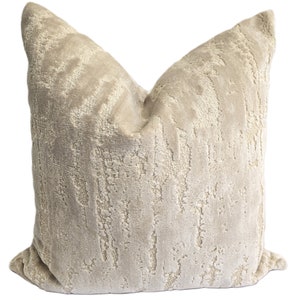 May include: A beige throw pillow with a textured, abstract pattern. The pillow is made of a soft, plush fabric.