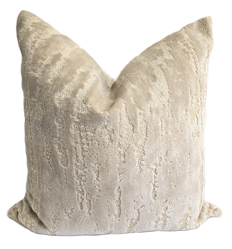 May include: A beige throw pillow with a textured, abstract pattern. The pillow is made of a soft, plush fabric.