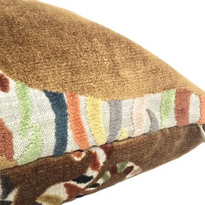 Peut inclure: Un coussin en velours marron avec un motif brod&eacute; color&eacute;. Le motif pr&eacute;sente une s&eacute;rie de rayures et de formes abstraites dans des tons de rose, orange, jaune, vert, bleu et gris.