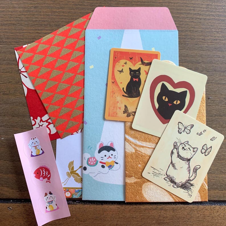 Flat lay of lucky cat mystery pack contents including memo sheets, stickers, pochi envelope and paper ephemera