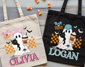 May include: Two canvas tote bags, one beige and one black, featuring ghost graphics with a black cat, a pumpkin-themed drink, and a checkered pattern. The beige bag displays the name Olivia in pink, and the black bag displays the name Logan in blue.