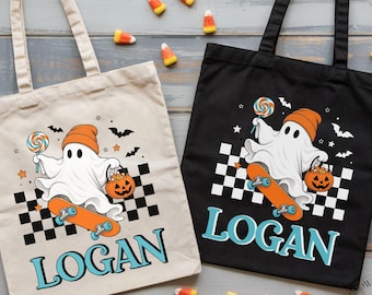 May include: Two tote bags, one beige and one black, each featuring a graphic of a ghost wearing an orange beanie, riding a skateboard, holding a lollipop and a jack-o'-lantern bucket. Below the graphic, the name LOGAN is printed in blue.