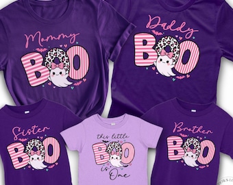 May include: A set of five purple t-shirts featuring Halloween-themed graphics. Four shirts display the word BOO with a ghost and leopard print, labeled Mommy, Daddy, Sister, and Brother. The center shirt is light purple with the text this little is One.