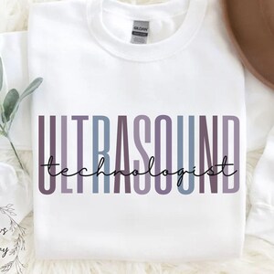 May include: White sweatshirt with the text "ULTRASOUND technologist" in a colorful gradient design.