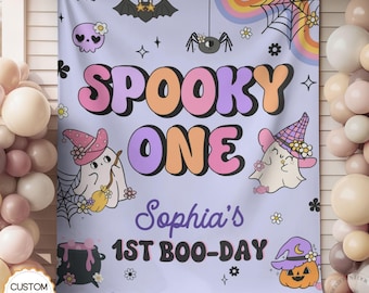 May include: A light purple fabric backdrop featuring the text SPOOKY ONE, Sophia's 1ST BOO-DAY, and illustrations of ghosts in hats, a black cauldron, bats, a spider, a spiderweb, a pumpkin, and rainbows. The design includes flowers and stars.
