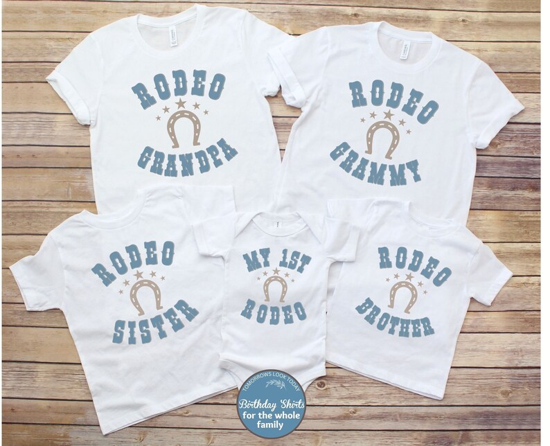 May include: Set of five white t-shirts with blue and brown text and a horseshoe graphic. The shirts say "Rodeo Grandpa", "Rodeo Grammy", "Rodeo Sister", "My 1st Rodeo", and "Rodeo Brother".