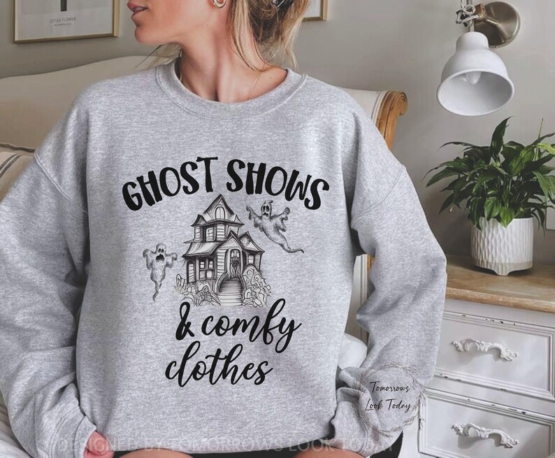 May include: Gray sweatshirt with a black graphic print of a haunted house, ghosts, and the text "Ghost Shows & Comfy Clothes".