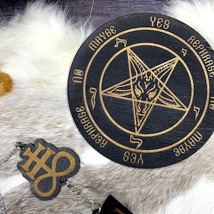 May include: Black wooden divination board with gold lettering and a pentagram design. The board has the words "Yes", "Maybe", "Rephrase", and "No". A matching keychain with a symbol and a triangle pendant is attached.