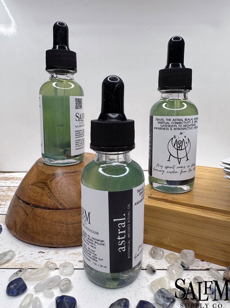 May include: Three glass bottles with dropper tops filled with a green liquid. The bottles are labelled "astral" and "TRAVEL THE ASTRAL REALM, DEEPEN SPIRITUAL CONNECTIVITY & OPEN GATEWAYS TO HEIGHTENED AWARENESS & INTROSPECTIVE VISION". The bottles are sitting on a wooden surface with white and blue stones.