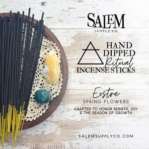 May include: A wooden tray holds a bundle of dark incense sticks with yellow tips, alongside crystals and a doily. Text reads "Salem Supply Co." and "Hand Dipped Ritual Incense Sticks". The label says "Eostre Spring Flowers".