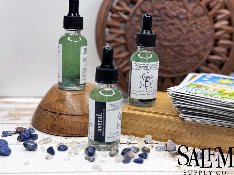 May include: Three glass bottles with dropper tops filled with a green liquid and crystals. The bottles have labels with text that reads "astral" and "Save the Astral Realm". The bottles are on a wooden surface with blue and white stones.