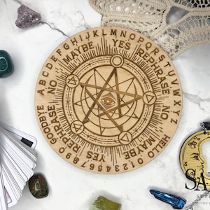 May include: A round wooden planchette board with engraved letters, numbers, and symbols. The board includes the words "YES", "NO", and "MAYBE". A crescent moon charm and crystals surround the board.