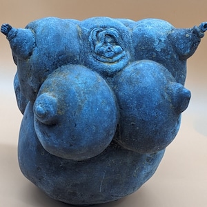 May include: A blue ceramic sculpture with a rounded, abstract form. The sculpture has multiple rounded protrusions and a textured surface.