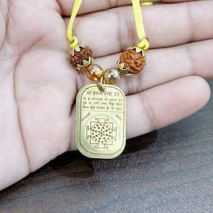 Colgante Baglamukhi 100% Metal Asthadhatu Color Dorado Con 5 Cuentas Mukhi Rudraksha Energizadas