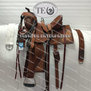 May include: A brown leather saddle with intricate stitching and a tooled design. The saddle is complete with a matching bridle, breast collar, and cinch. The saddle is decorated with silver conchos and buckles.