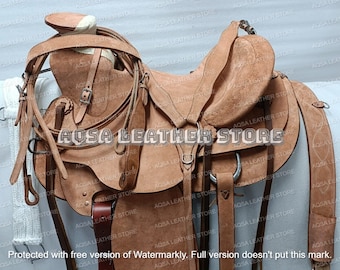 May include: A brown leather saddle with a white cinch and stirrups. The saddle is decorated with stitching and a silver concho.