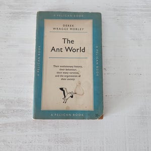 May include: A vintage paperback book titled "The Ant World" by Derek Wragge Morley. The book has a blue and white cover with the text "A Pelican Book." The cover features a drawing of a bird. The book's condition shows signs of age.