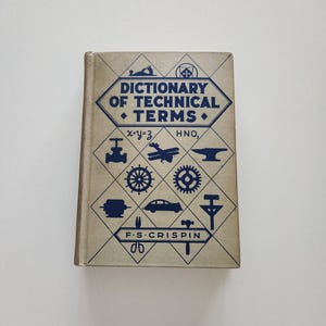 May include: A vintage book titled "Dictionary of Technical Terms" with blue text and illustrations on a tan cover. The cover features geometric shapes and symbols related to engineering and science. The author's name, F.S. Crispin, is also visible.