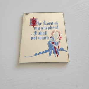 May include: A small, rectangular, gold-colored mirror with a white background. The mirror has a blue and red image of a shepherd with a staff and sheep. The text "The Lord is my shepherd. I shall not want." is printed in red and blue.