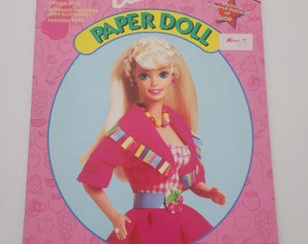 May include: A vintage Barbie Paper Doll book. The cover shows a Barbie doll in a pink outfit. The book is a deluxe edition and includes precut fashions and accessories. The Golden Books logo is visible. The text 'Paper Doll' is prominent.