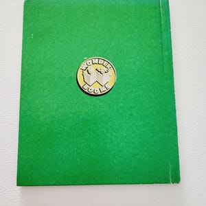 Może przedstawiać: Tylna okładka zielonej książki w twardej oprawie z złotym logo Wonder Books przedstawiającym dwoje dzieci czytających.