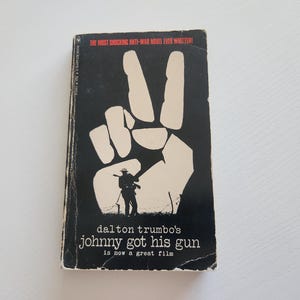 May include: A black and white book cover with a peace sign and the text "THE MOST SHOCKING ANTI-WAR NOVEL EVER WRITTEN" and "dalton trumbo's johnny got his gun is now a great film".