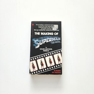 May include: A paperback book titled The Making of Superman The Movie by David Michael Petrou. The black cover features the Superman logo, a film strip graphic with four images of the character, and the text 16 Pages of Photos.