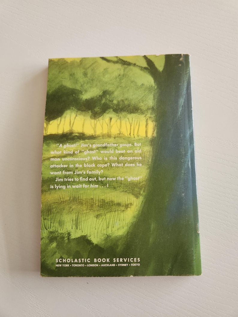 Pode incluir: Uma capa de livro com uma ilustra&ccedil;&atilde;o verde e amarela de uma floresta. O texto na capa diz: "Um fantasma!" O av&ocirc; de Jim ofega. Mas que tipo de "fantasma" poderia bater em um velho at&eacute; deix&aacute;-lo inconsciente? Quem &eacute; esse atacante perigoso com a capa preta? O que ele quer da fam&iacute;lia de Jim? Jim tenta descobrir, mas agora o "fantasma" est&aacute; esperando por ele...!