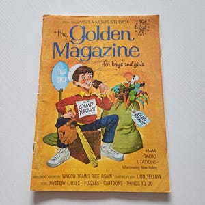 May include: Vintage "The Golden Magazine" cover. The cover is yellowed with age and features a cartoon illustration of a boy holding a microphone, a parrot, and the text "for boys and girls". Additional text includes "Camp Yukalot".