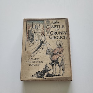 May include: Vintage book titled "The Castle of Grumpy Grouch" with a cover illustration of a person on horseback approaching a castle. The book's cover is aged with visible wear and tear, and the author's name is "Mary Dickerson Donahey."