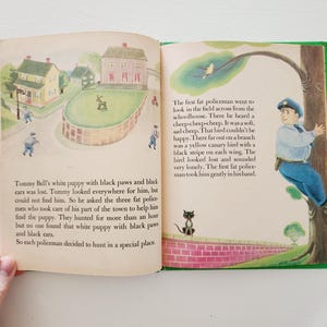 Może przedstawiać: Otwarta książka z kolorową ilustracją policjanta pomagającego ż&oacute;łtemu kanarkowi. Tekst na stronie brzmi "Tommy Bell's white puppy with black paws and black ears was lost. Tommy looked everywhere for him, but could not find him. So he asked the three fat policemen who took care of his part of the town to help him find the puppy. They hunted for more than an hour but no one found that white puppy with black paws and black ears. So each policeman decided to hunt in a special place."