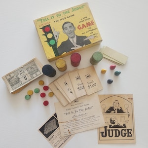 May include: Vintage board game titled "Tell It To The Judge" with a box featuring a man and a traffic light. Includes game cards, wooden tokens, play money, and a "Judge" card. A classic game for all motorists.