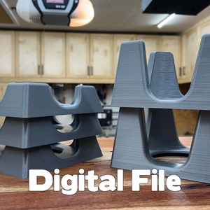 Puede incluir: Dos juegos de organizadores de plástico gris impresos en 3D, apilados uno encima del otro. Los organizadores tienen un diseño en forma de U con múltiples compartimentos. Los organizadores están sobre una superficie de madera. Archivo digital.