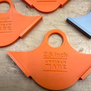 May include: Several orange and one grey artisan-made tools with a handle and angled edge. The tools are labelled with measurements: 2 inches, 2.5 inches, and 1.75 inches. The text "ARTISAN MADE" is also printed on each tool.