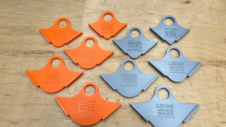 May include: A selection of orange and grey artisan-made measuring tools. The tools are labelled with inch measurements ranging from 0.64 cm to 6.35 cm. Each tool has a handle and the text "ARTISAN MADE".