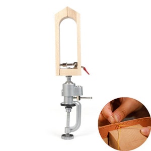 May include: A wooden leather stitching clamp with a metal base and a clamp. The clamp has a lever to tighten the stitching area. The clamp is attached to a metal base with a screw. The base has a clamp to secure it to a table or workbench. A hand is shown stitching leather with a needle and thread.
