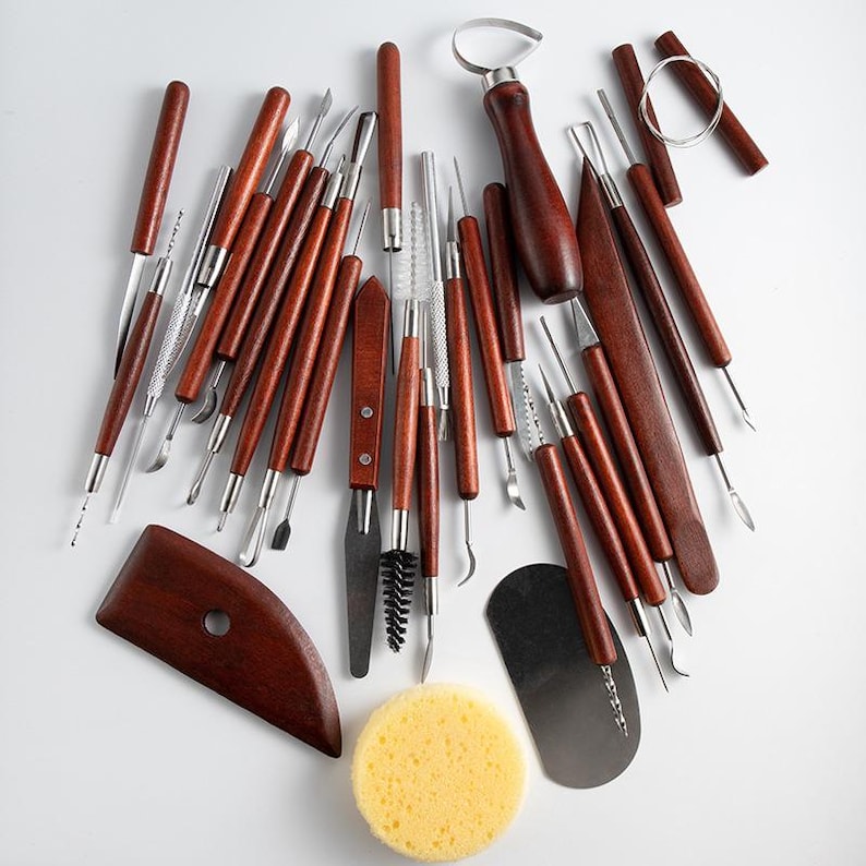 May include: A set of 28 pottery tools with wooden handles and stainless steel tips. The tools include a variety of shapes and sizes for sculpting, smoothing, and shaping clay. The set also includes a sponge and a scraper.